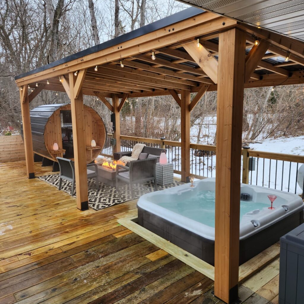deck with sauna, fire pit, and hot tube with snow in the background